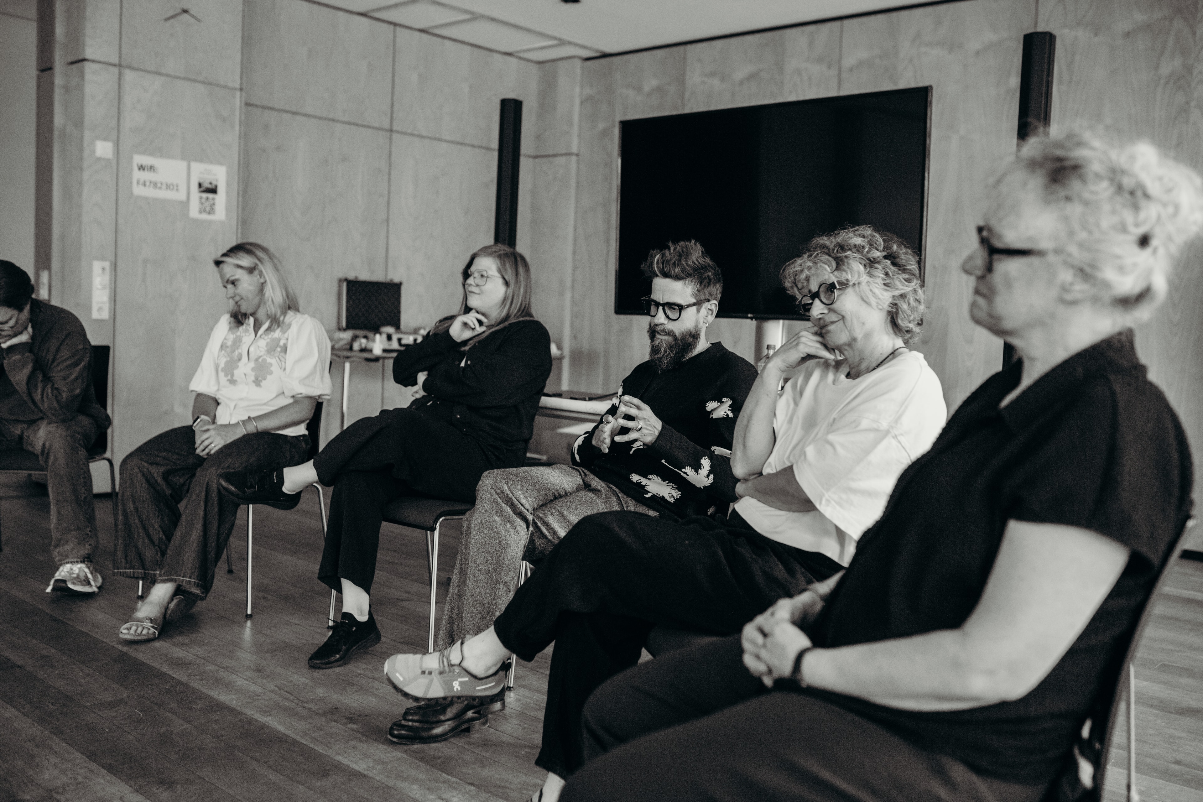 A group of people sitting in a circle in a room, engaging in a thoughtful discussion.
